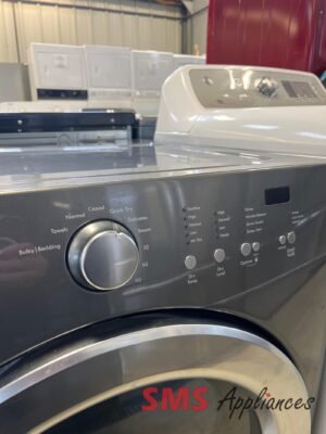 Close-up of a front-loading washing machine control panel with a large dial and various cycle options in a showroom setting, with 'SMS Appliances' watermark visible.